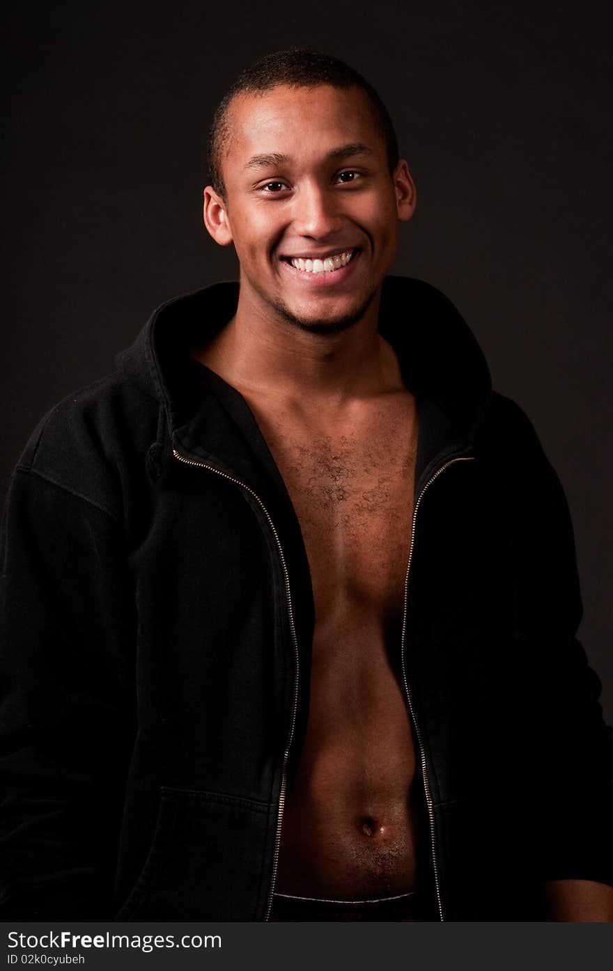 Young muscular male in hood on black background