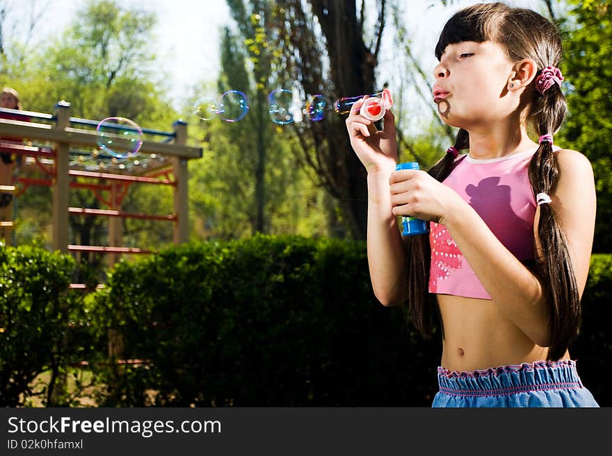 Nice girl with soap bubbles in park