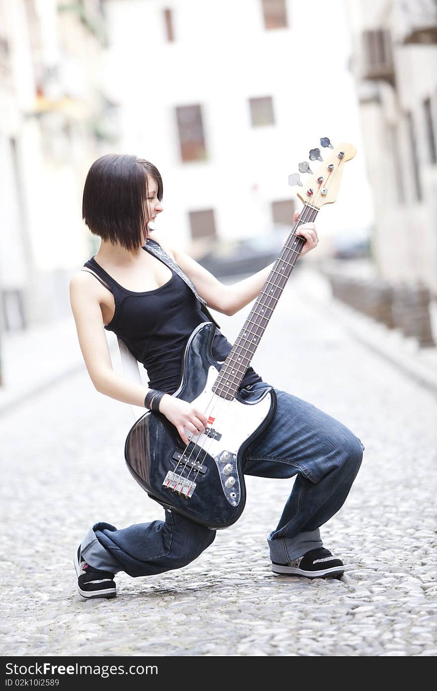 Joyful young woman playing a guitar at the street. Joyful young woman playing a guitar at the street