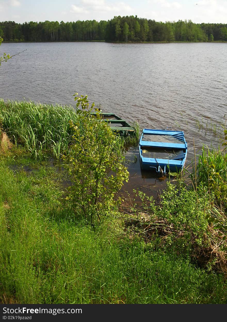 Two old fishing boat full of water at the edge of the pond