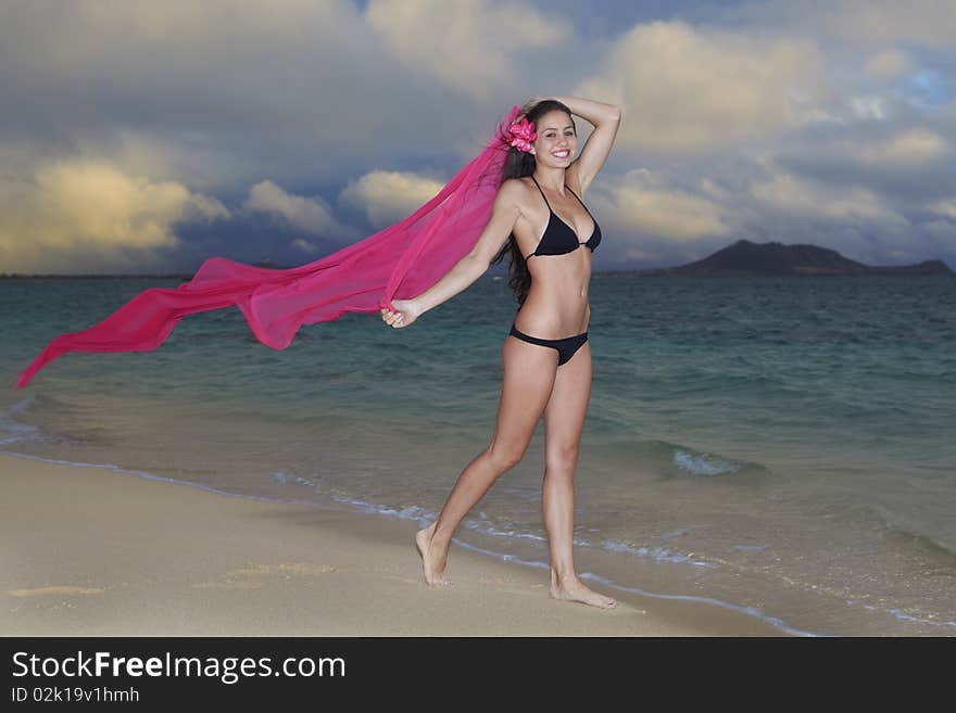 Beautiful young woman on lanikai beach at sunrise in a bikini with a long chiffon scarf