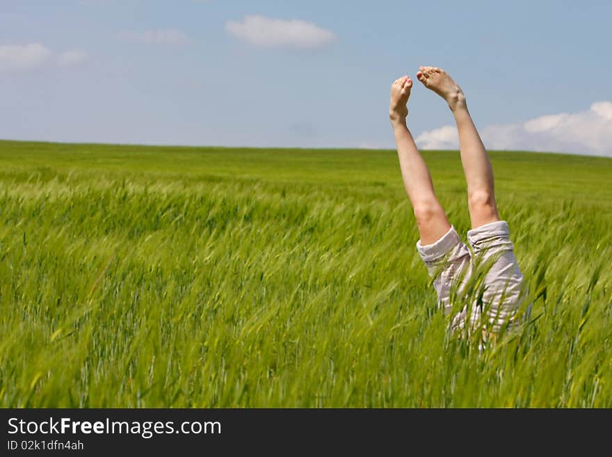 Female legs raised up from green grass