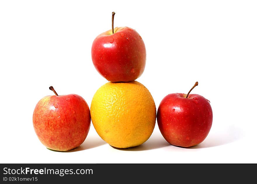 Red apples and orange in pyramid with shadow isolated over white