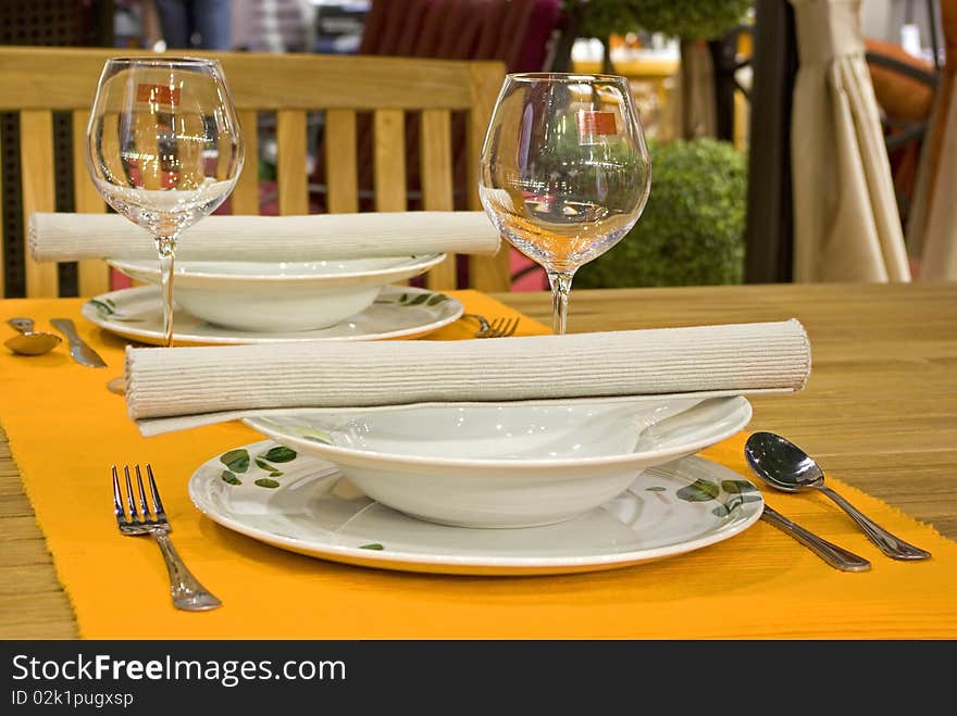 White dinner set on orange doily with silver cutlery