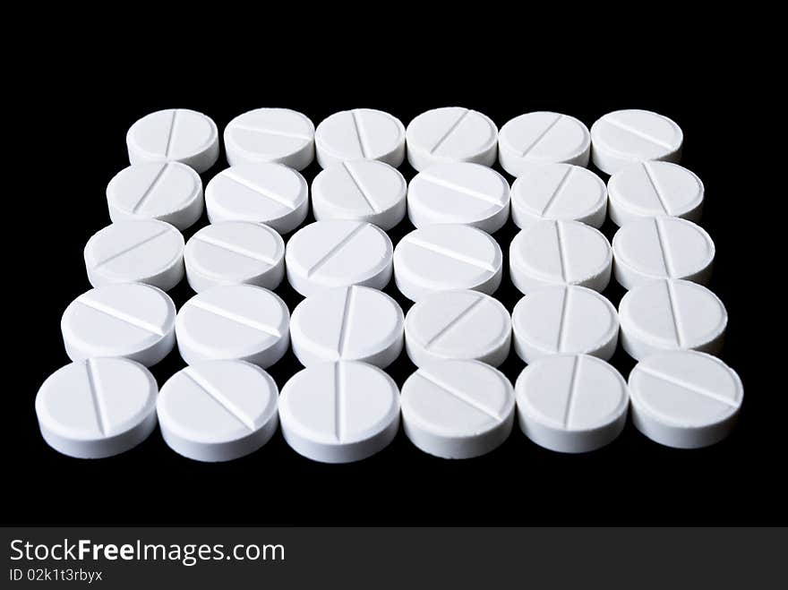 White pills arranged on the black background