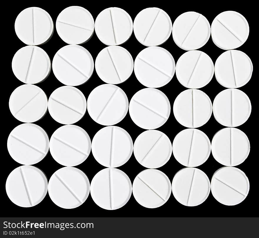 White pills arranged on the black background