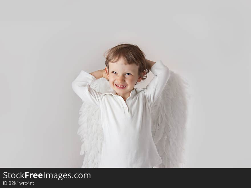 Beautiful little angel boy, white clothes, wings, blue eyes