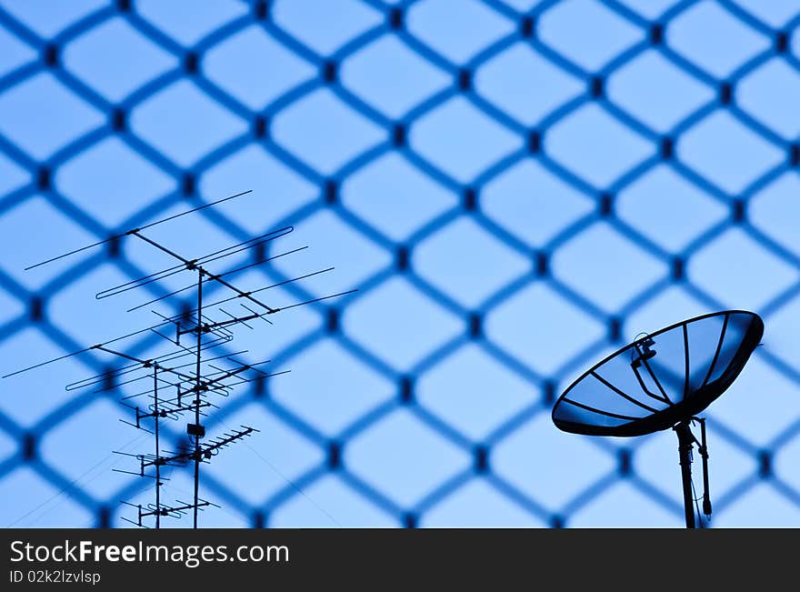 Wire fence with satellite in blue sky