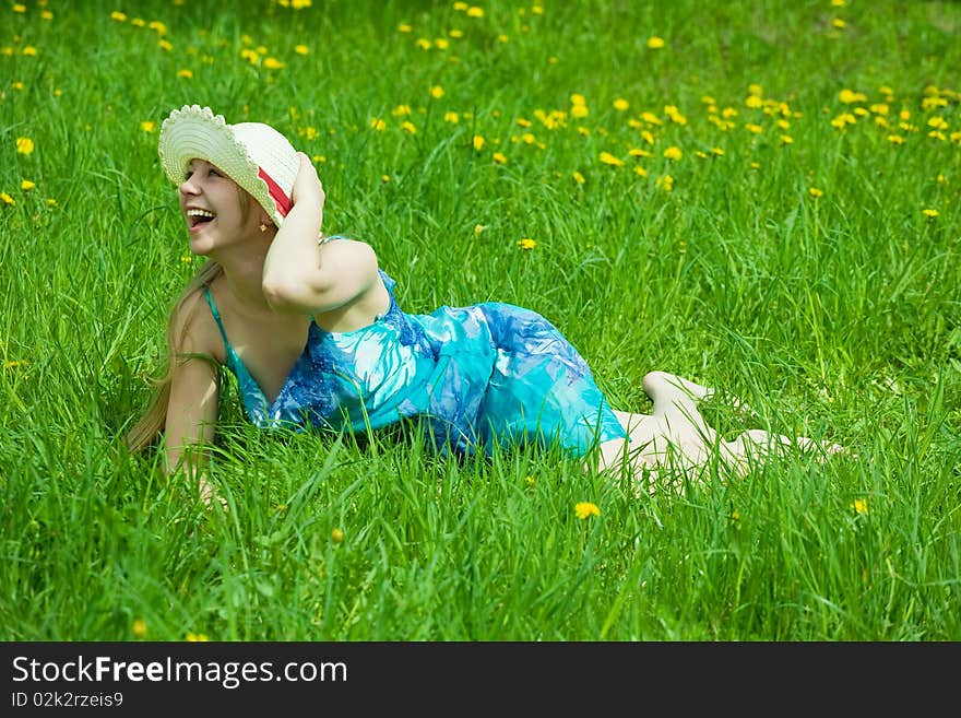 Pretty smiling  girl in hat relaxing in grass outdoor