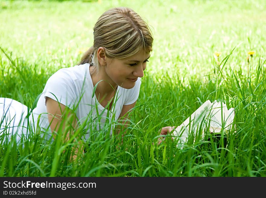 Young girl is laying on the grass with a book. Young girl is laying on the grass with a book