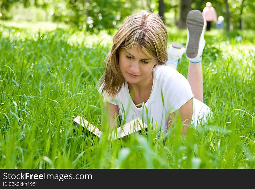 Young girl is laying on the grass with a book. Young girl is laying on the grass with a book