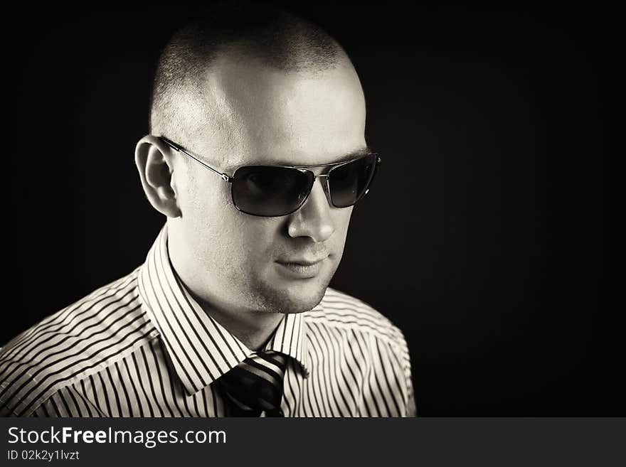 Young man with sunglasses posing on a black background