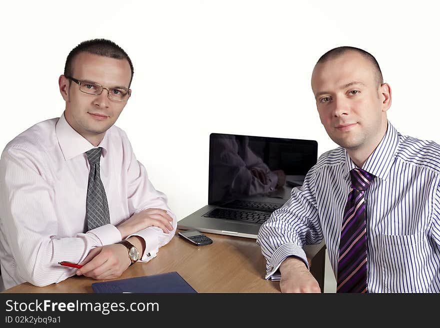 Two businessmen looking at camera with laptop behind. Two businessmen looking at camera with laptop behind