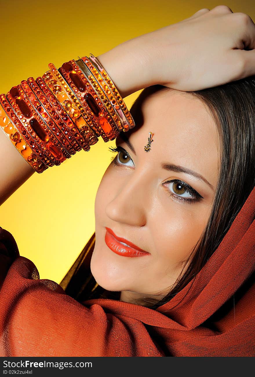 Young beautiful woman in indian traditional jewellary, bindi and sari dress. yellow background. Young beautiful woman in indian traditional jewellary, bindi and sari dress. yellow background