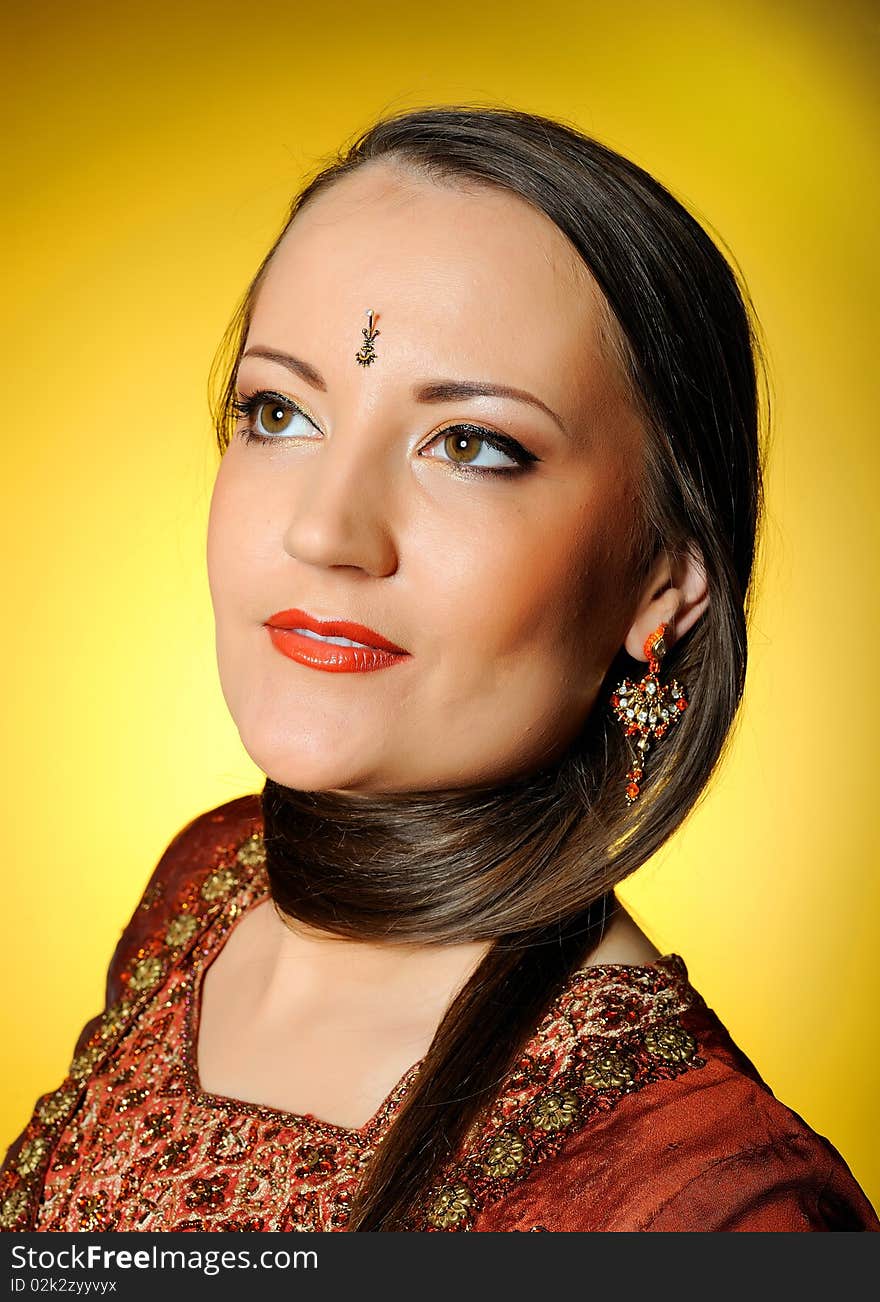 Young beautiful woman in indian traditional jewellary, bindi and sari dress. yellow background. Young beautiful woman in indian traditional jewellary, bindi and sari dress. yellow background