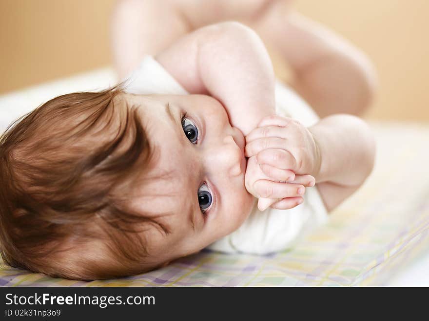 Cute baby boy with hands in mouth; shallow DOF, focus on eyes