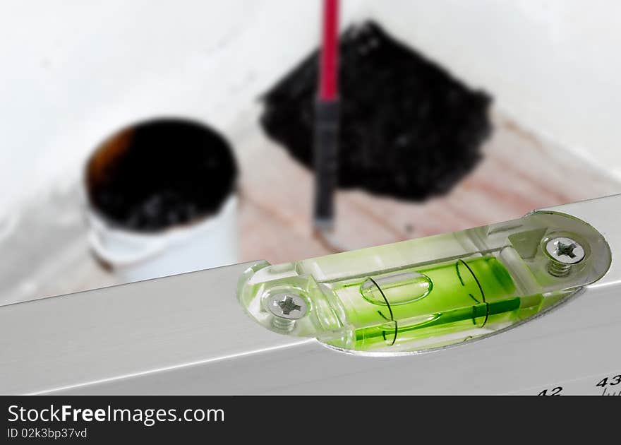 Spirit level against a wooden floor that being prepared for flattening with a hydroisolating mastique on a background. Spirit level against a wooden floor that being prepared for flattening with a hydroisolating mastique on a background