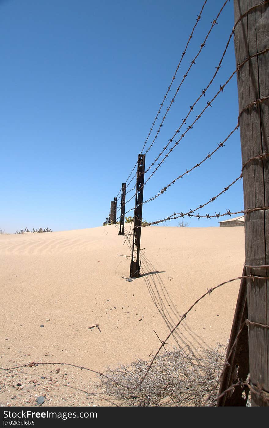 Old barbed wire fence in the desert with blue sky, Namibia.