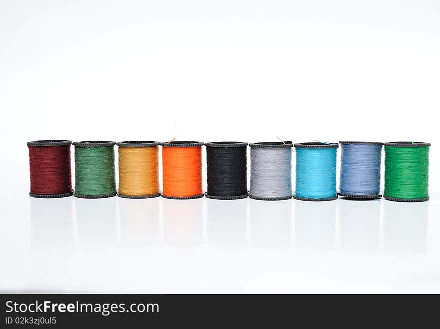 Colorful thread spools lined up on a white background. Colorful thread spools lined up on a white background.