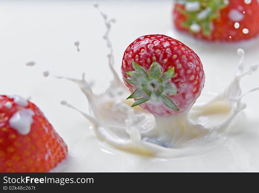 Fresh strawberries splashing in milk