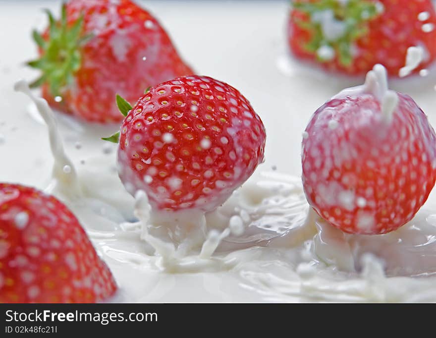 Fresh strawberries splashing in milk