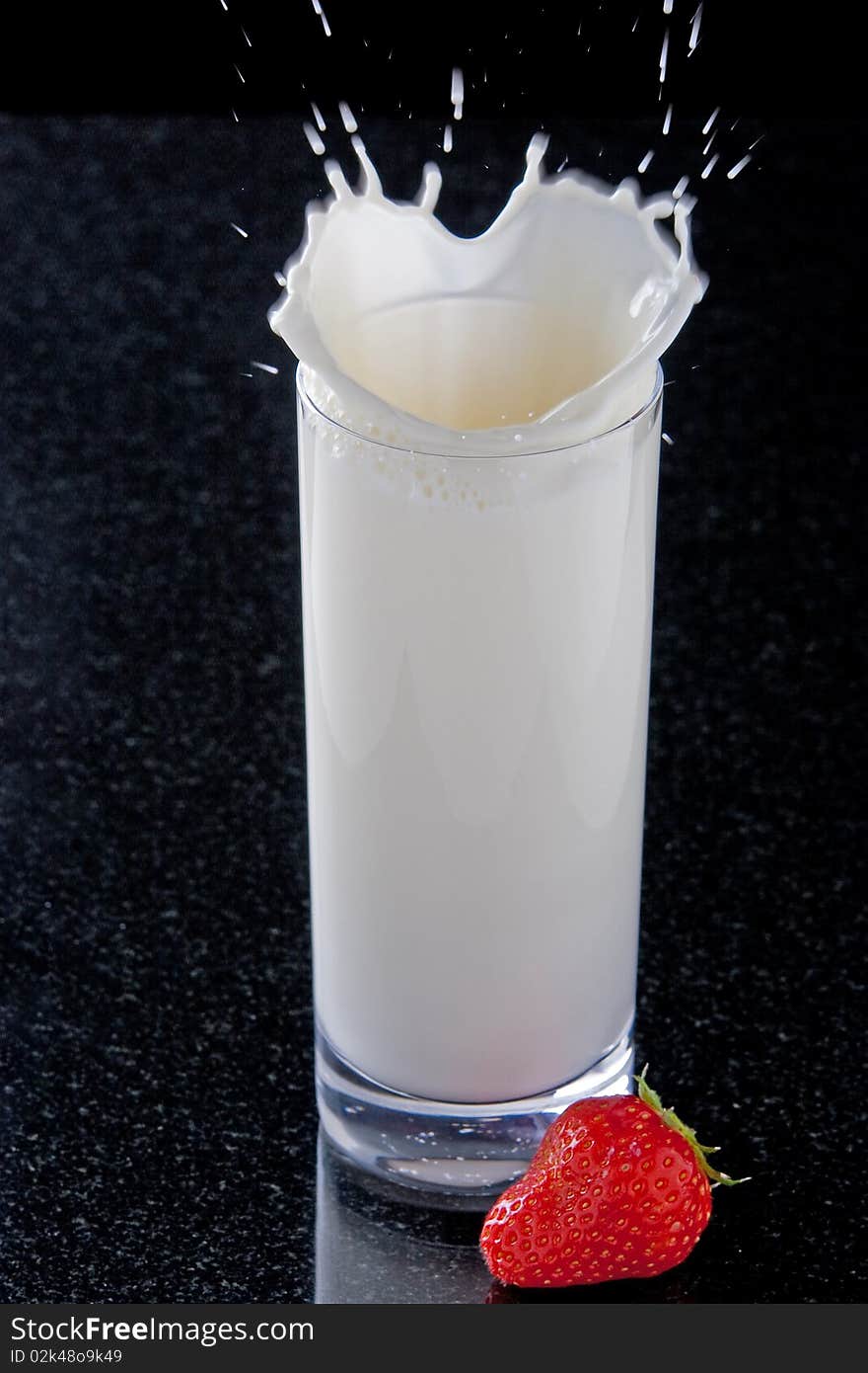 Strawberry splashing in glass of milk. Strawberry splashing in glass of milk