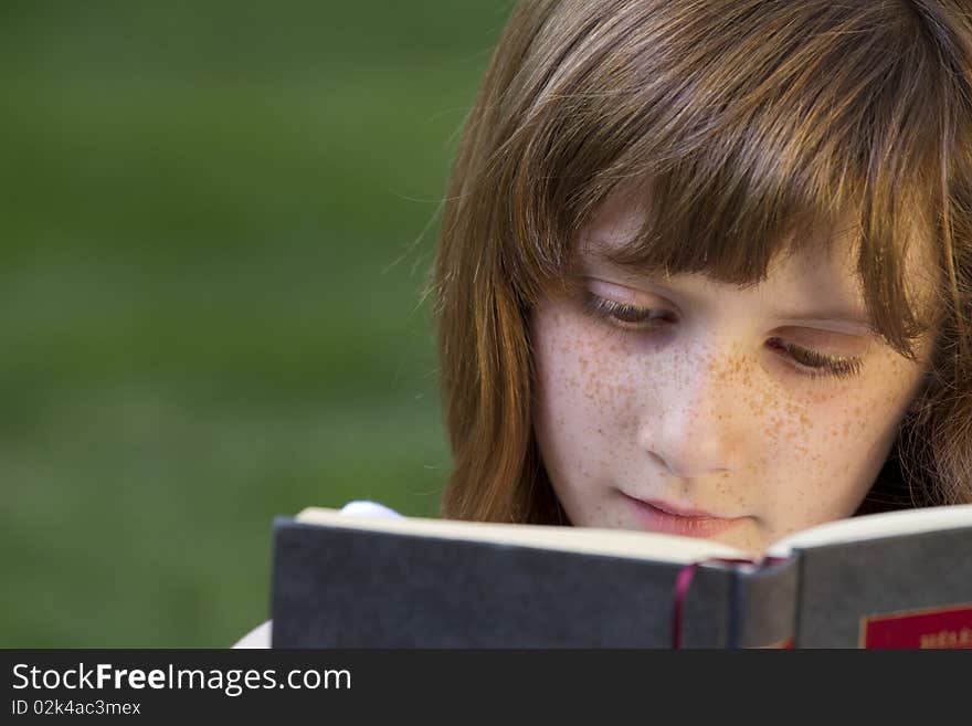 Young beautiful girl reading a book outdoor