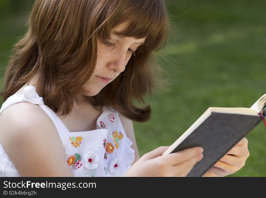 Young beautiful girl reading a book outdoor