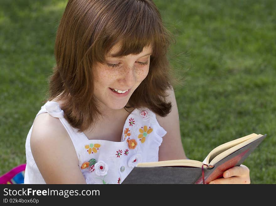 Young beautiful girl reading a book outdoor