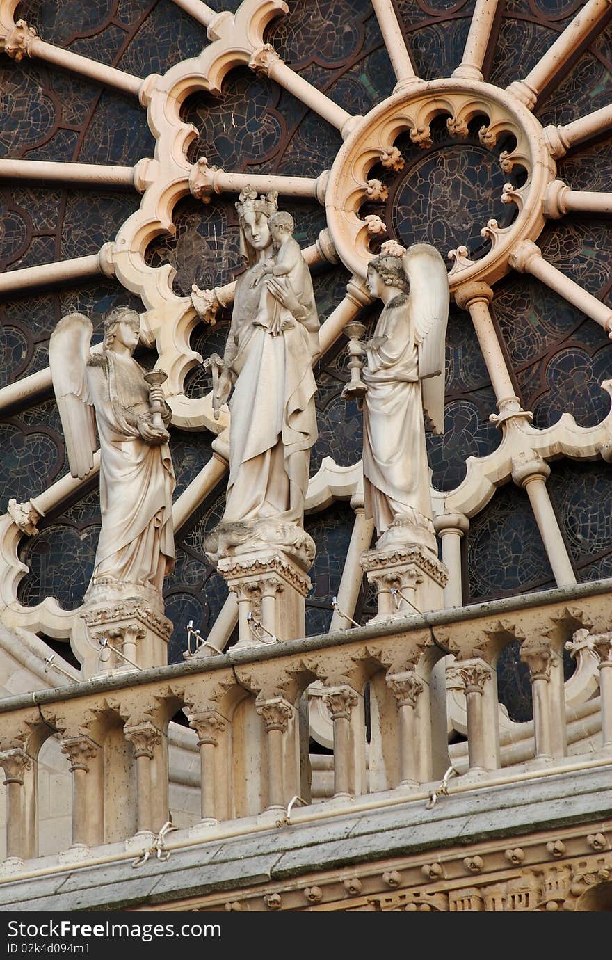 A statue of the Virgin Mary, Baby Jesus, and two angels in front of the rose window of the facade of the Notre Dame Cathedral, Paris, France. A statue of the Virgin Mary, Baby Jesus, and two angels in front of the rose window of the facade of the Notre Dame Cathedral, Paris, France