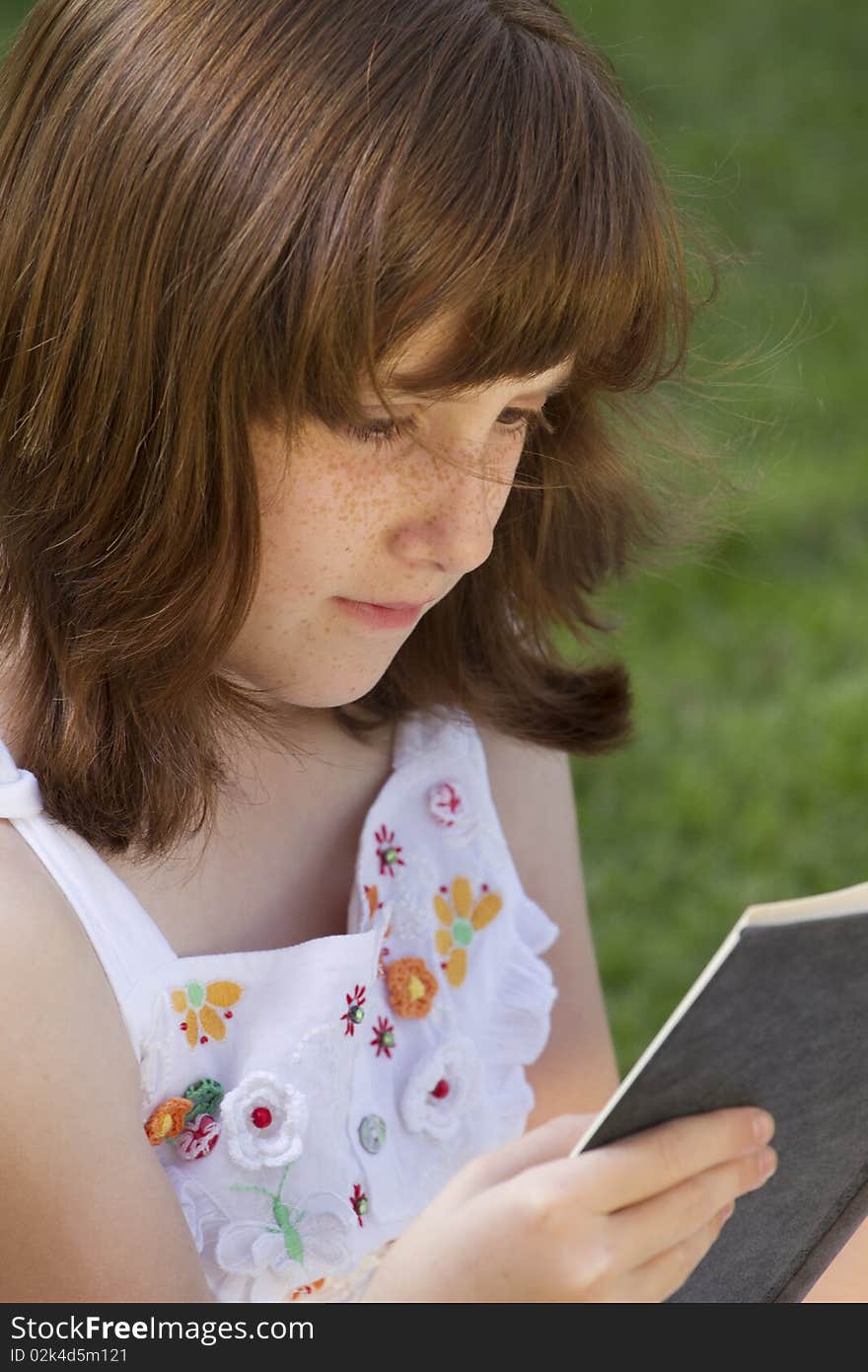 Young beautiful girl reading a book outdoor