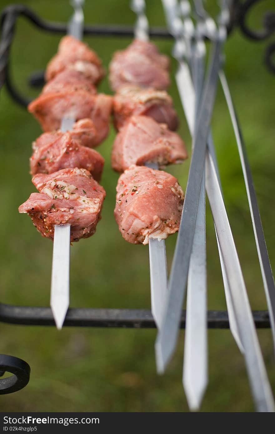 Marinated meat being prepared for cooking on metal skewers