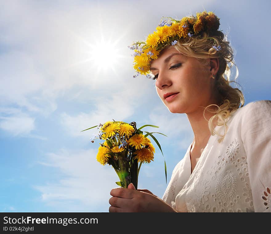 Beautiful woman with dandelion flowers over blue sky