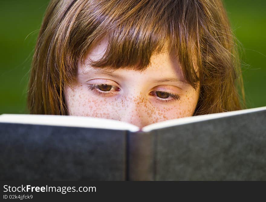 Young beautiful girl reading a book outdoor