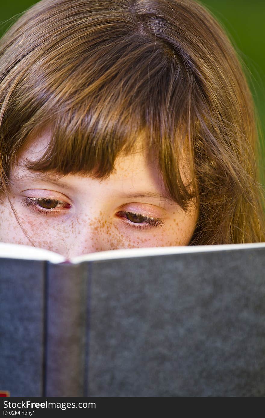 Young beautiful girl reading a book outdoor