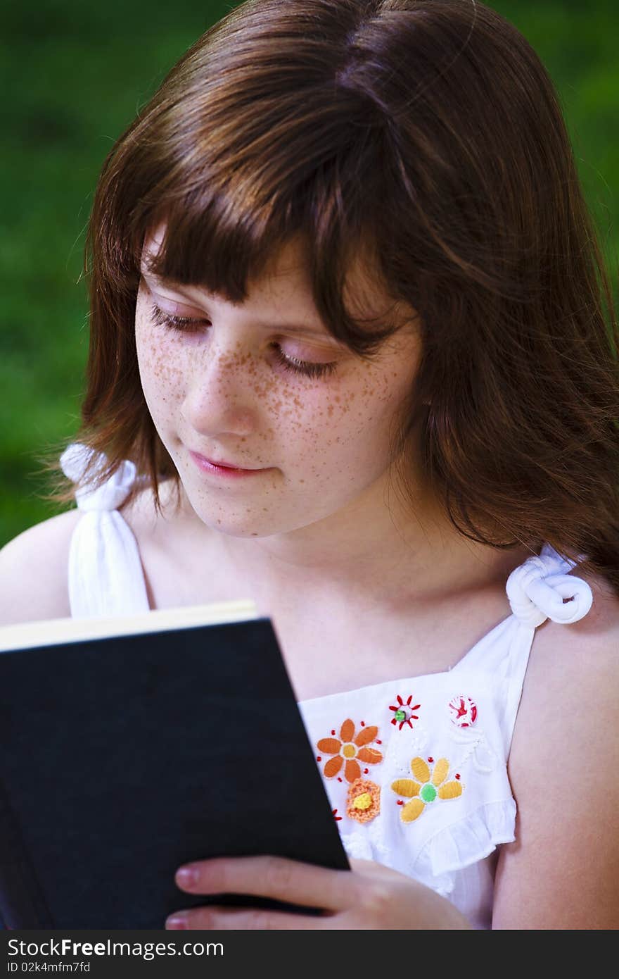 Young beautiful girl reading a book outdoor