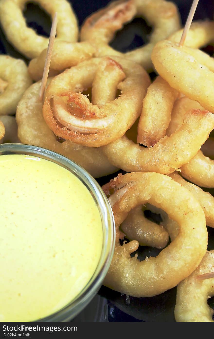 Close up of breaded, deep-fried squid on plate, garnished with aioli sauce. Close up of breaded, deep-fried squid on plate, garnished with aioli sauce