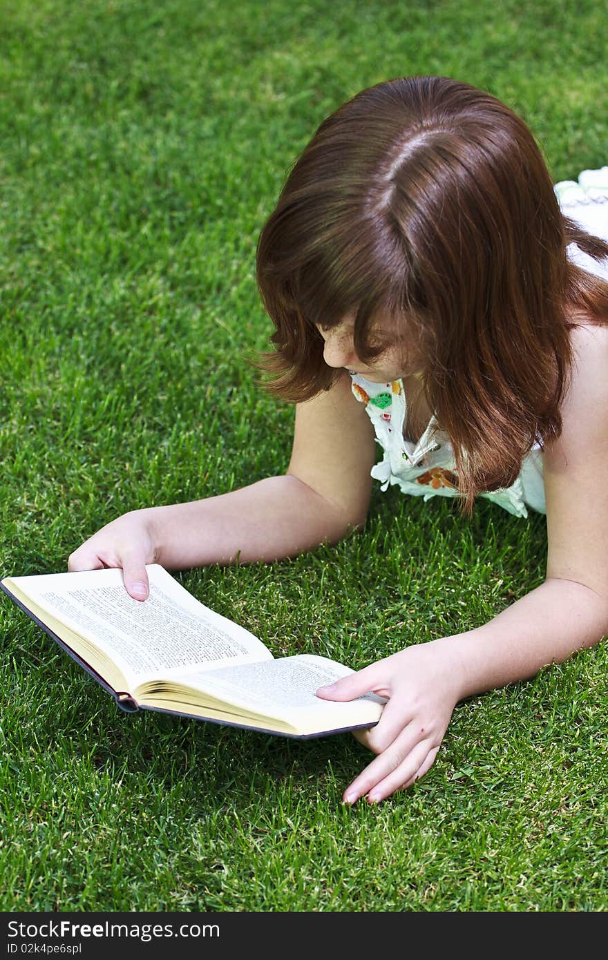 Young beautiful girl reading a book outdoor