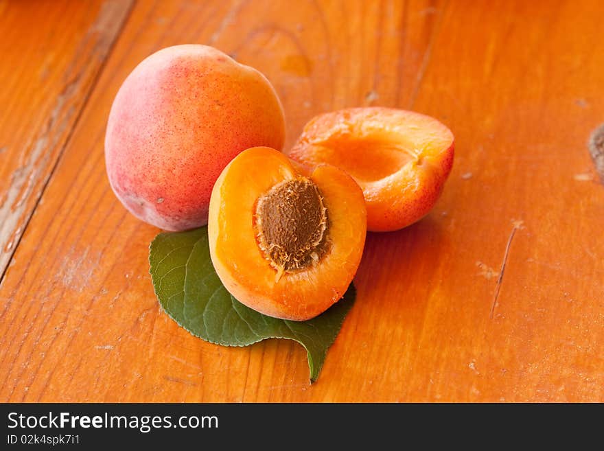 Apricots and leaf on wooden background