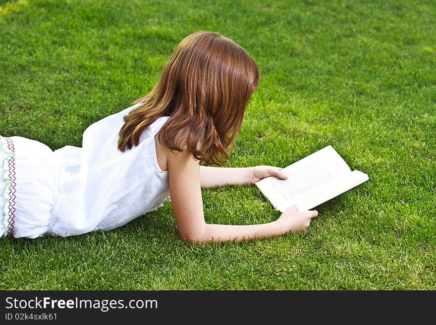 Young beautiful girl reading a book outdoor