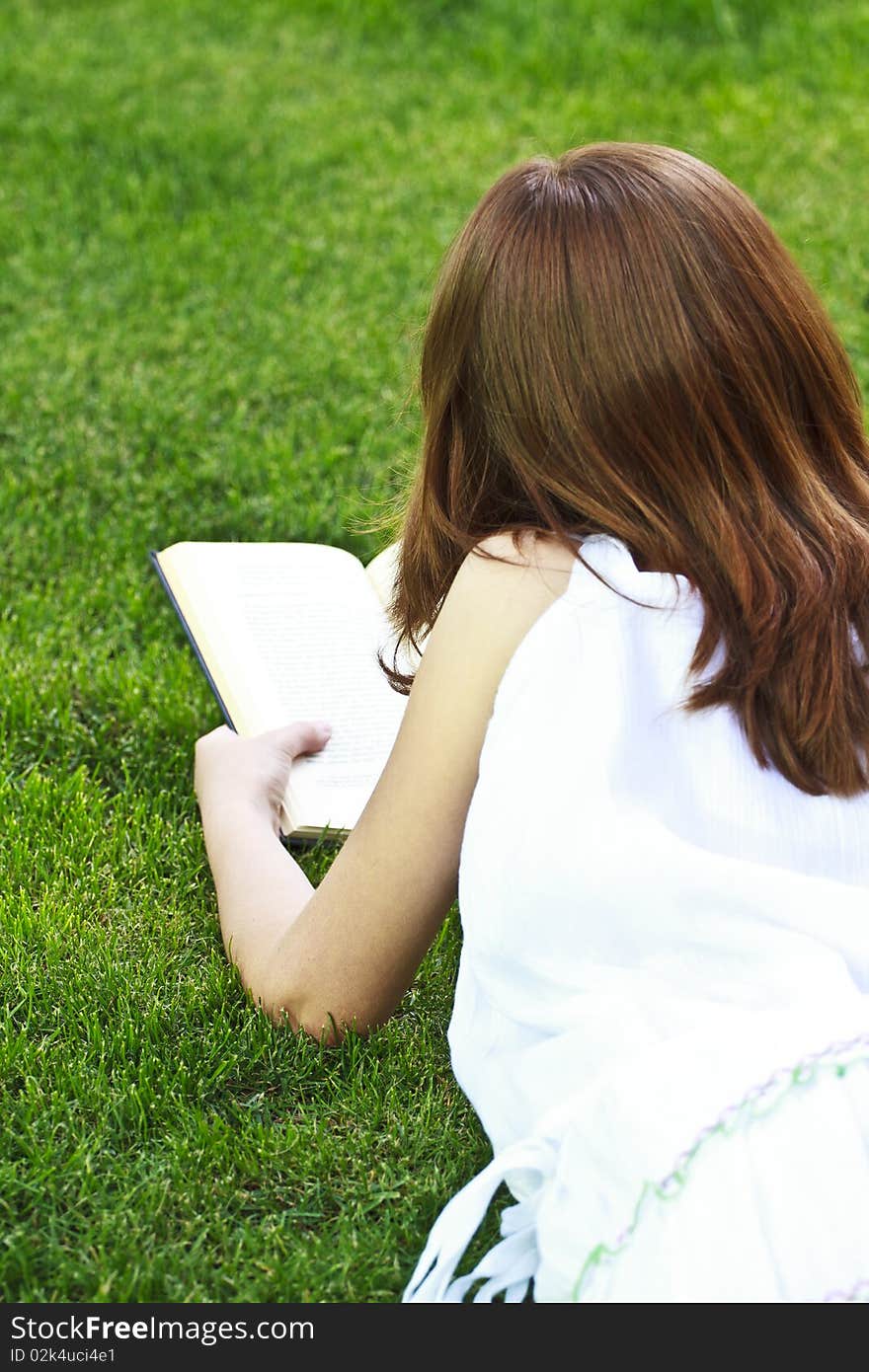 Young beautiful girl reading a book outdoor