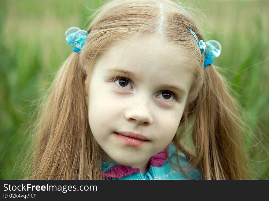 A little girl on a green meadow dressed warmly in a cold summer day