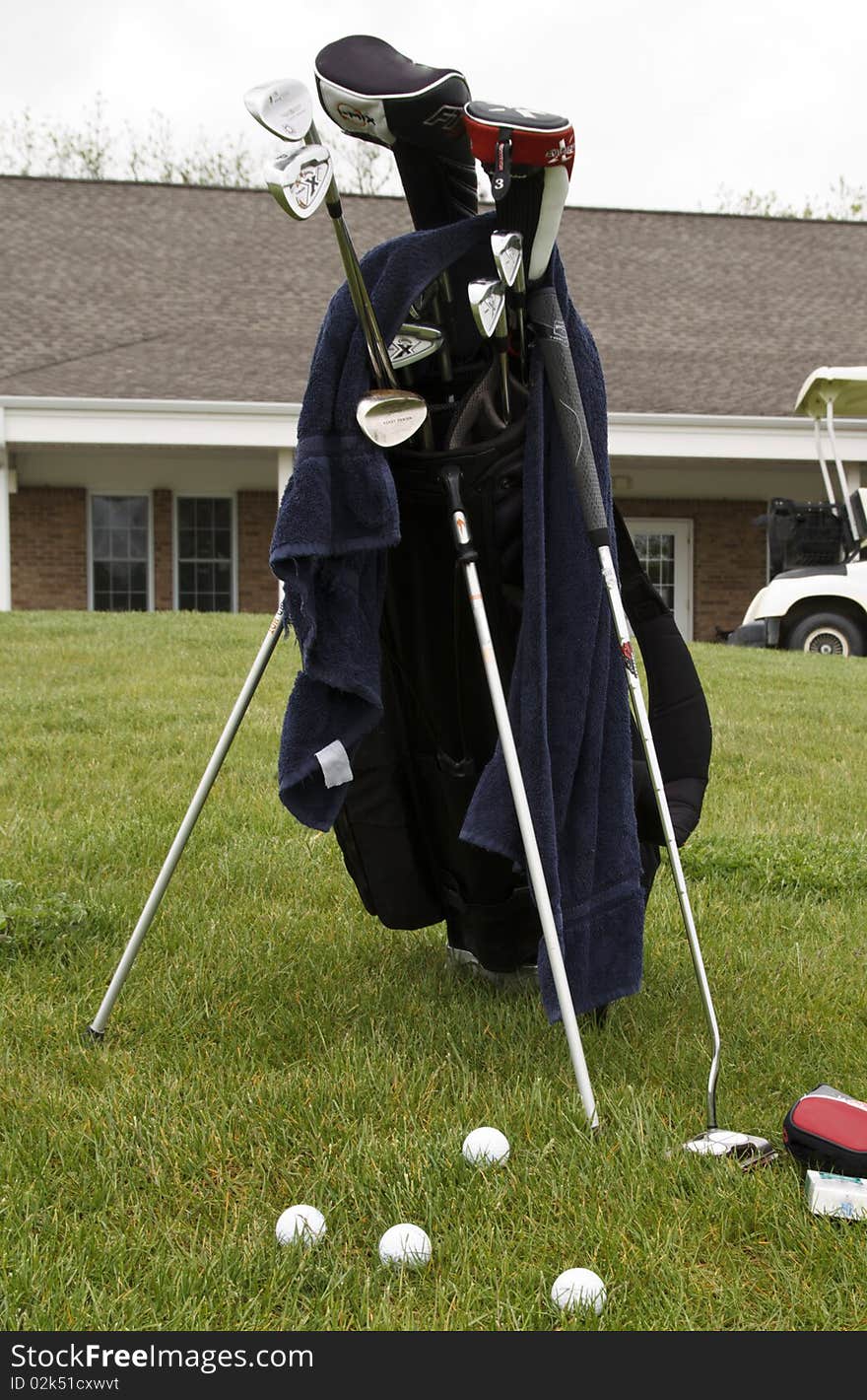 Golfer sets his clubs next to the green to practice. Golfer sets his clubs next to the green to practice