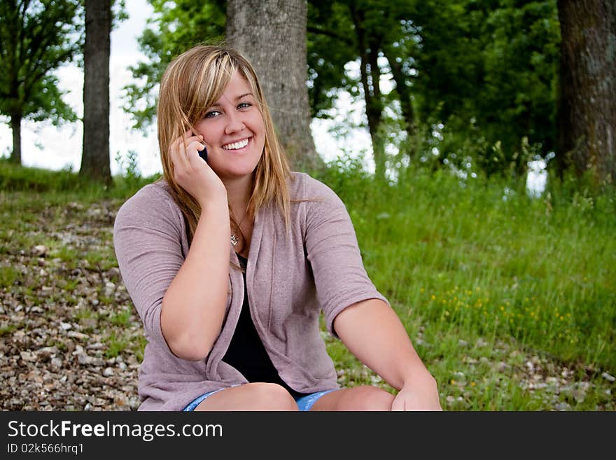 A young attractive teenage girl smiles and talks on the phone while looking at the camera. A young attractive teenage girl smiles and talks on the phone while looking at the camera.