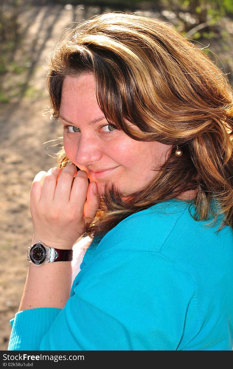 Smiling brunette outdoors; hair is lit by back-light