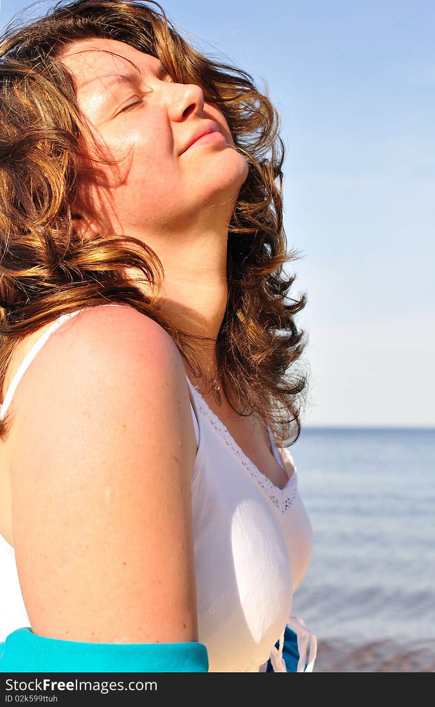 Brunette resting on the beach, eyes closed; warm lighting setup. Brunette resting on the beach, eyes closed; warm lighting setup