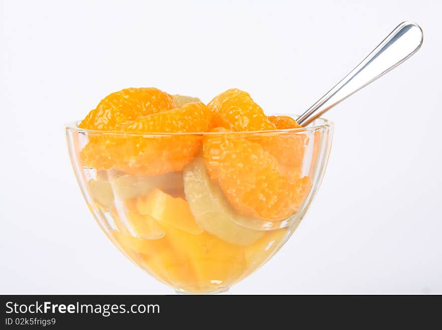 Fruit salad and a spoon on white background