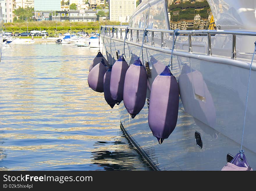 A number of bumpers hanging from the side of a yacht. A number of bumpers hanging from the side of a yacht