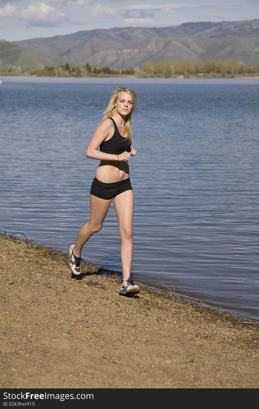 A woman is running on the beach wearing black shorts and a halter top. A woman is running on the beach wearing black shorts and a halter top.