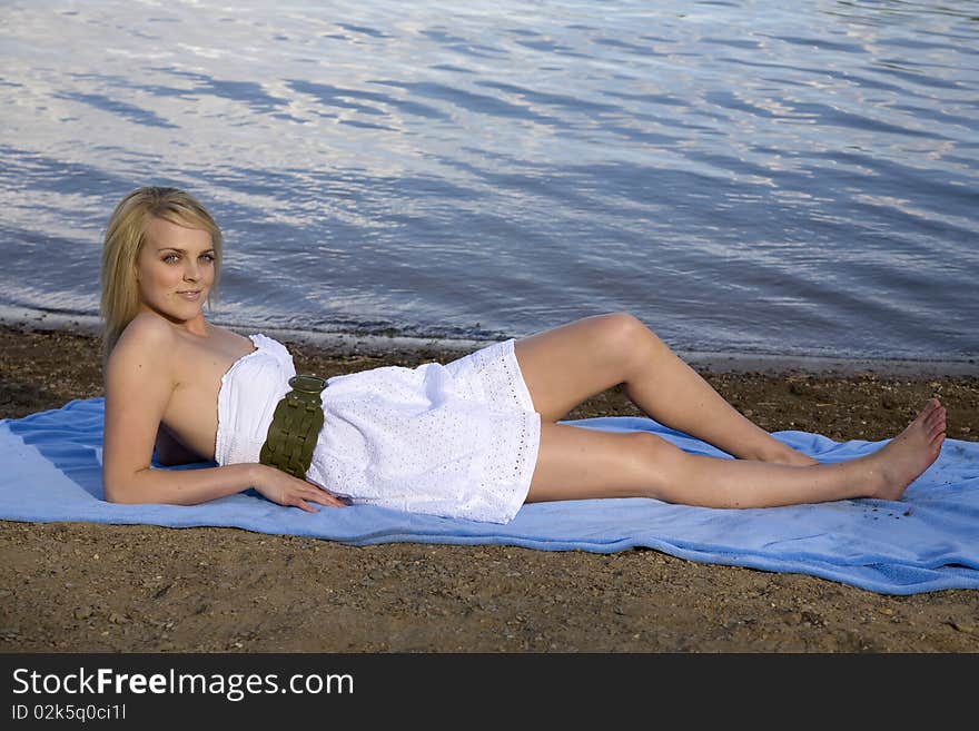 A beautiful woman laying on a blue blanket on the beach relaxing. A beautiful woman laying on a blue blanket on the beach relaxing.